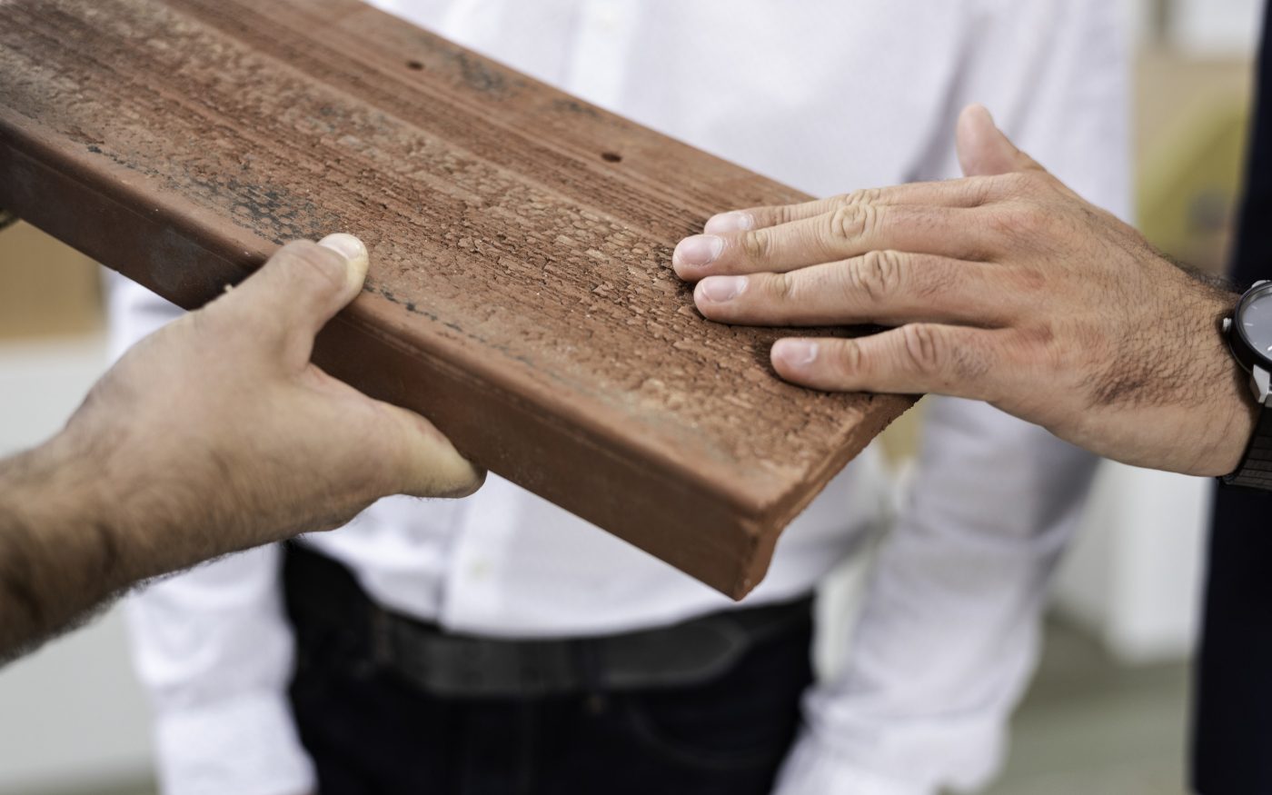 Hands touching surface structure of roof- and façade clay tile "Urban"