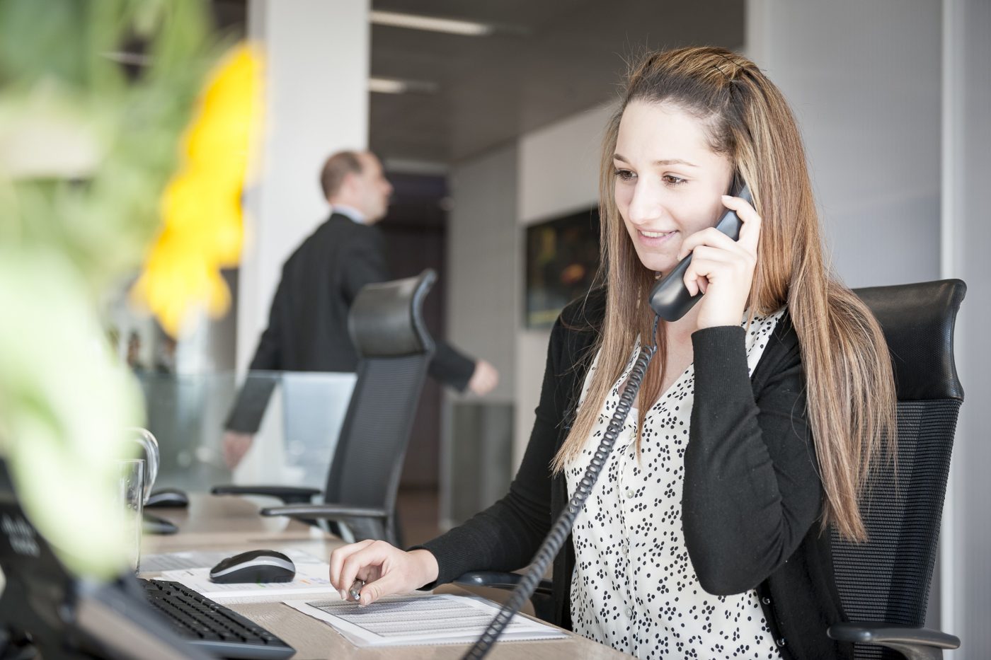 Young woman at reception desk holding telephone